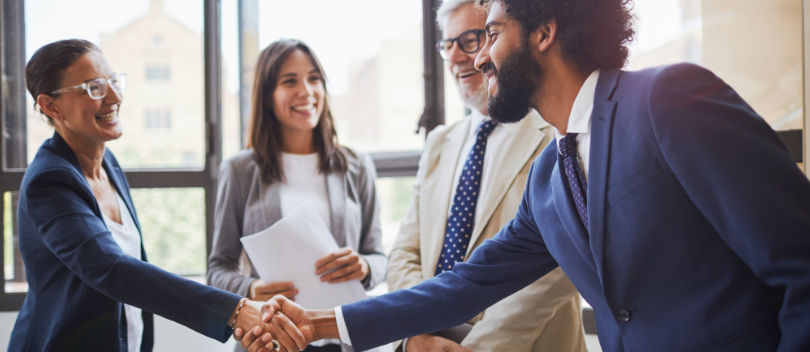 Image of 4 Caribbean board members looking happy and 2 of them shaking hands.