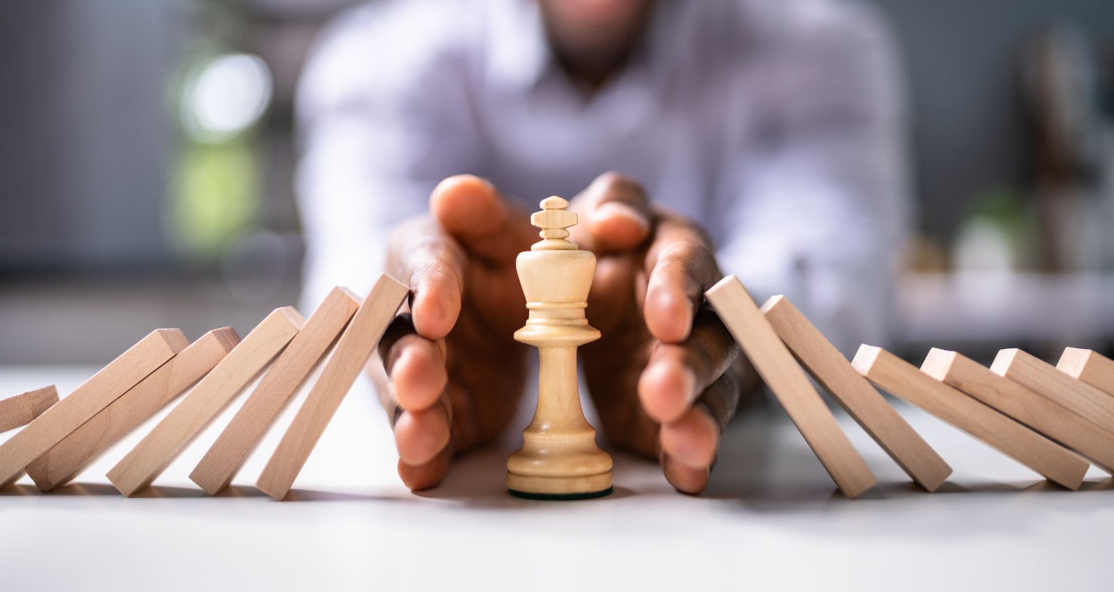 board cybersecurity helps minimise risk management like this man protecting his king from the dominos